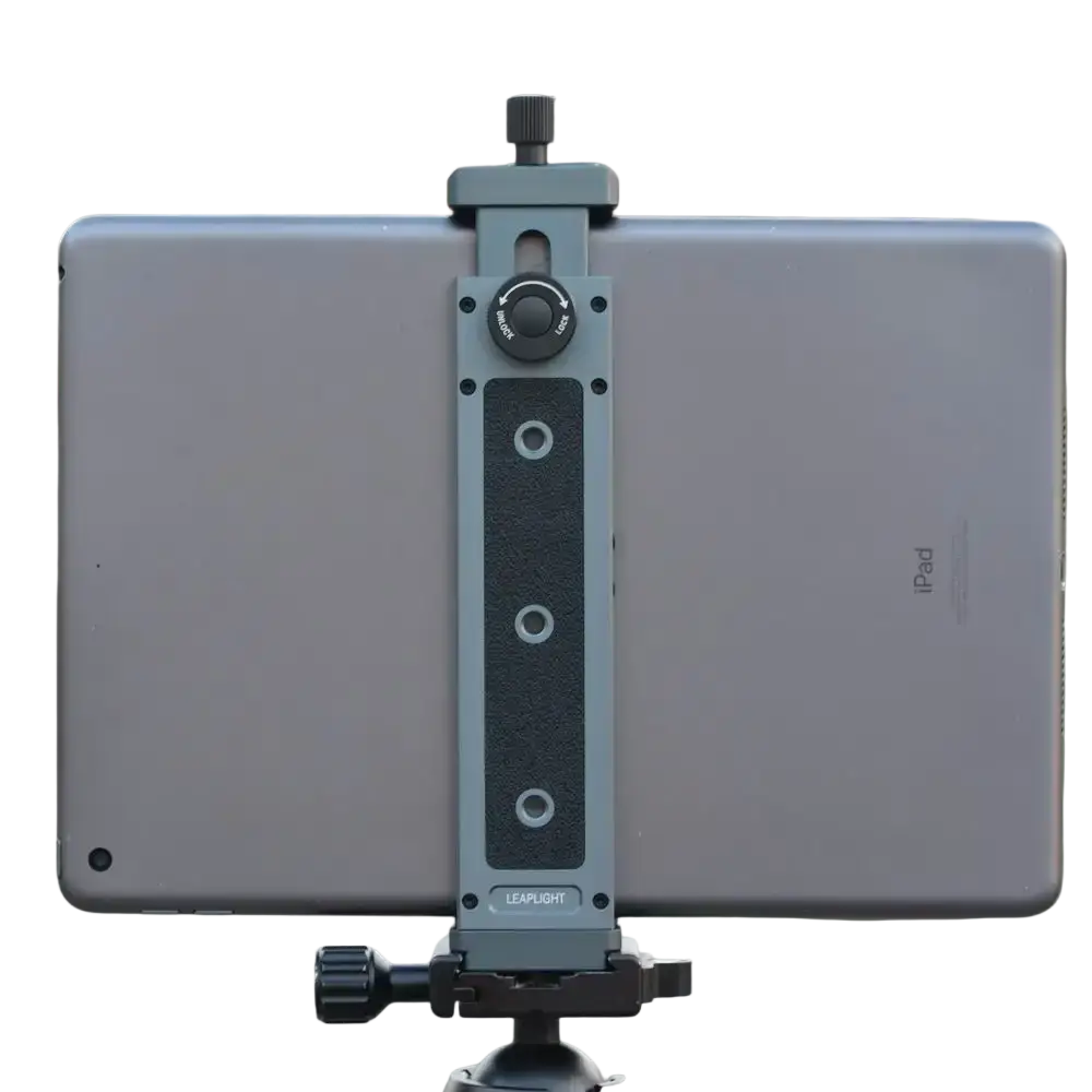 Gray aluminum tablet clamp with black rubber grip and adjustable knobs securing a silver iPad in a universal tripod mount adapter