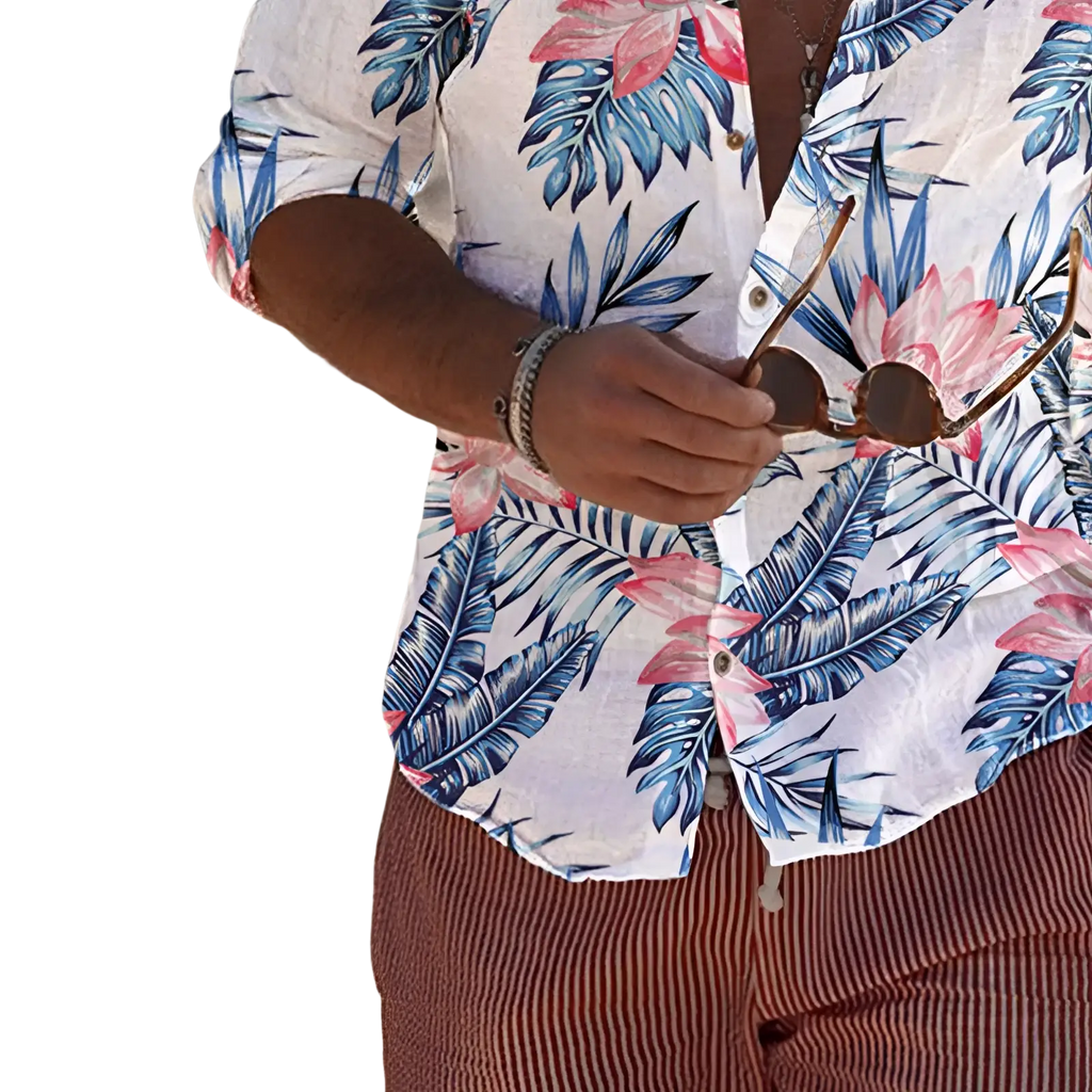 A man wearing a tropical print long sleeve mens beach shirt with vibrant blue and pink leaf patterns on white fabric