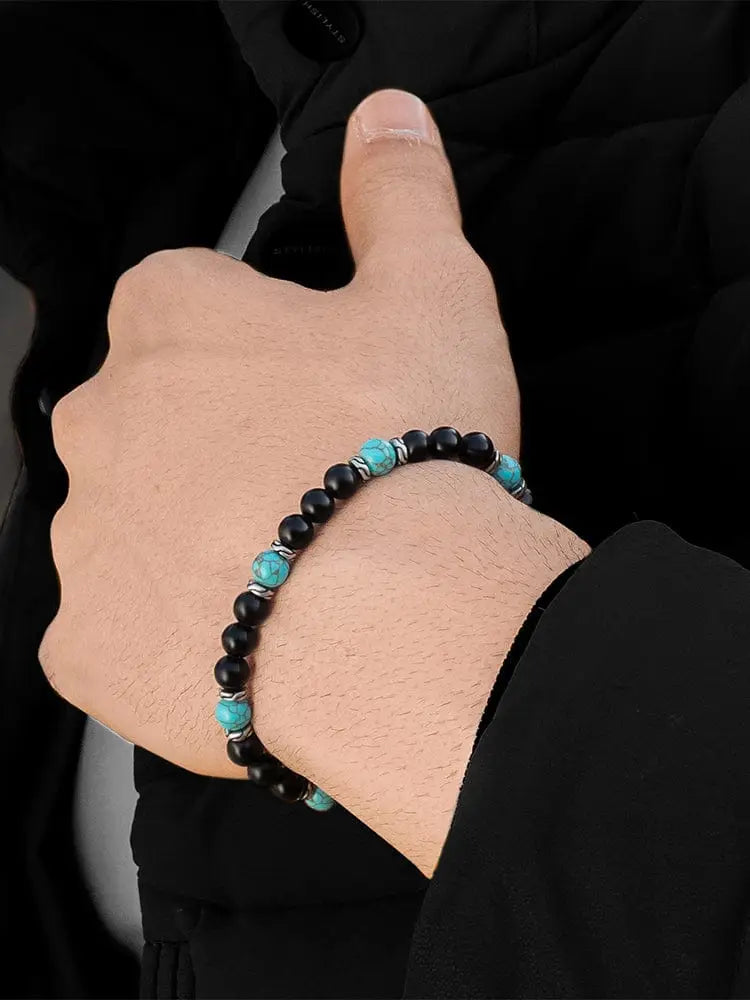 A navajo turquoise and black onyx adjustable beaded bracelet with silver spacers worn on a wrist