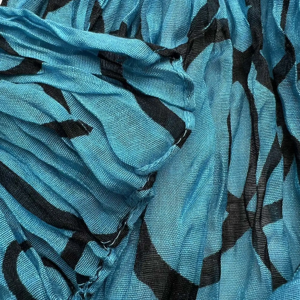 A soft flowing turquoise crinkle beach cover up scarf with bold black abstract patterns
