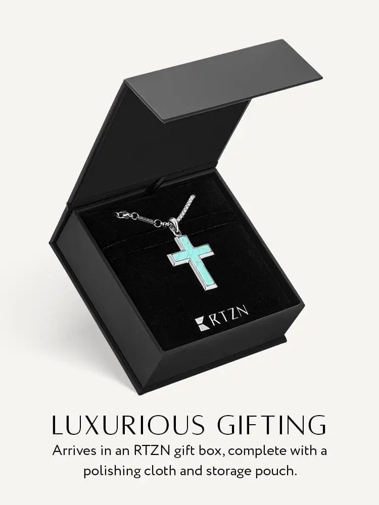A silver stainless steel cross pendant necklace with turquoise inlay displayed in an rtzn gift box on a chain