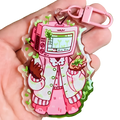 Pink acrylic tv head anime keychain featuring a cartoon character in a pink and white patterned coat bag charm