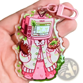 Pink acrylic tv head anime keychain featuring a cartoon character in a pink and white patterned coat bag charm
