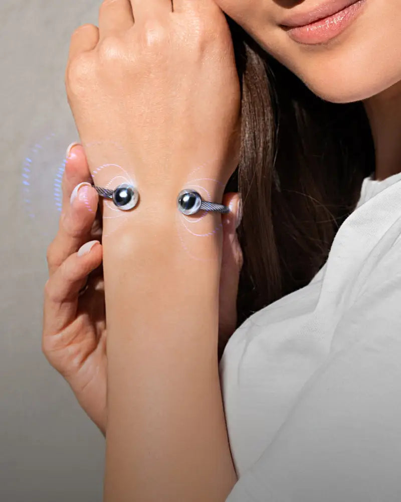 Silver-toned twisted cable magnetic cuff bracelet featuring two prominent black spherical beads on band