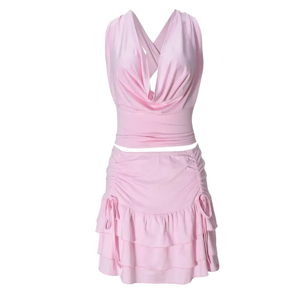 A soft pink two piece mini skirt set with pullover closure featuring a sleeveless halter top and ruched tiered skirt