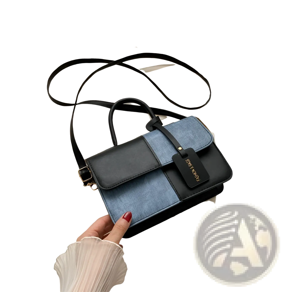 Two tone denim patchwork crossbody bag in black and blue with a sleek leather handle and adjustable strap