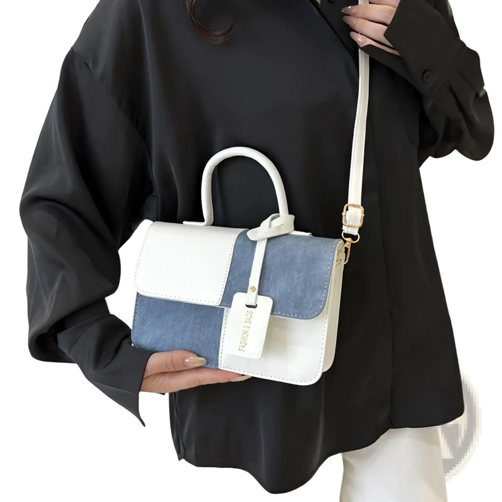 Two tone denim patchwork crossbody bag with white and denim blue panels, structured design, top handle, and gold hardware