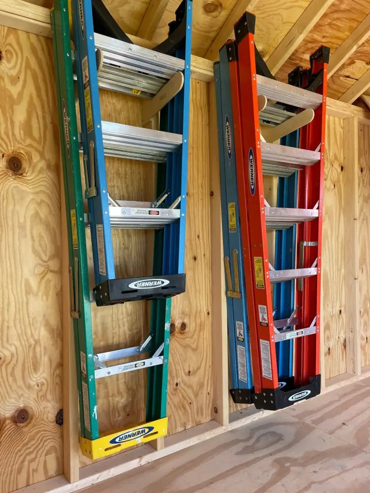 Two Werner brand ladders in green and red mounted vertically on wooden wall in ultimate garden tool wall organizer kit