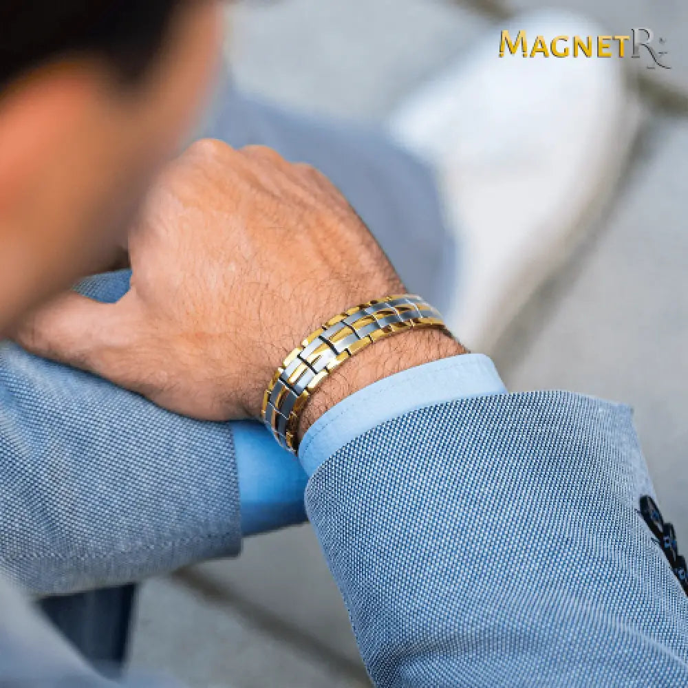 A sleek two tone magnetic therapy bracelet with alternating gold and silver links worn on a mans wrist from Magnetrx