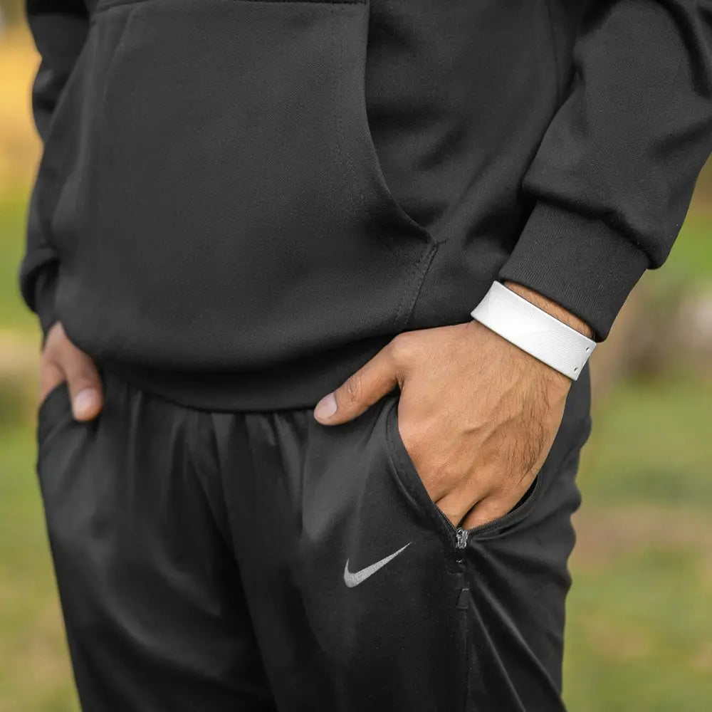 Black nike athletic pants with silver swoosh logo and zipper pocket paired with white ultra strength neodymium magnetic sports bracelet