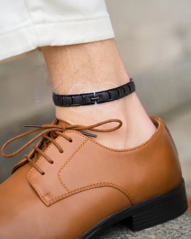 Men’s black titanium magnetic therapy anklet with sleek segmented design and small engraved label shown from the back