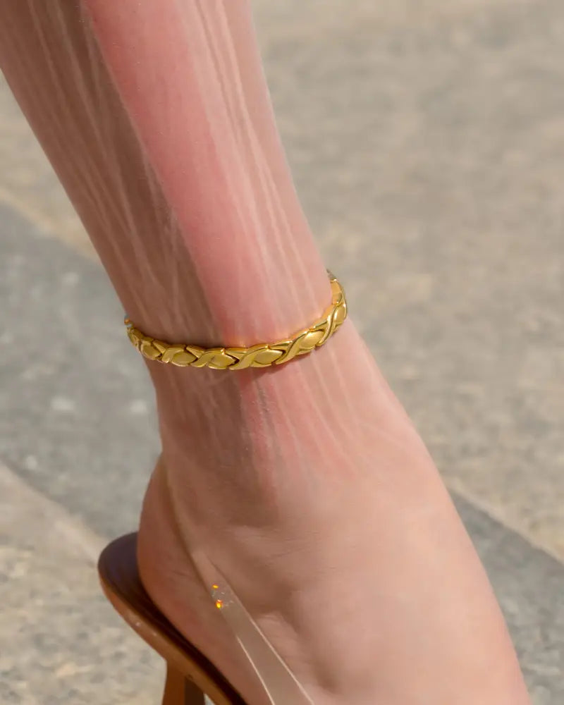 A delicate gold-toned ultra strength titanium magnetic therapy anklet with an intricate braided design