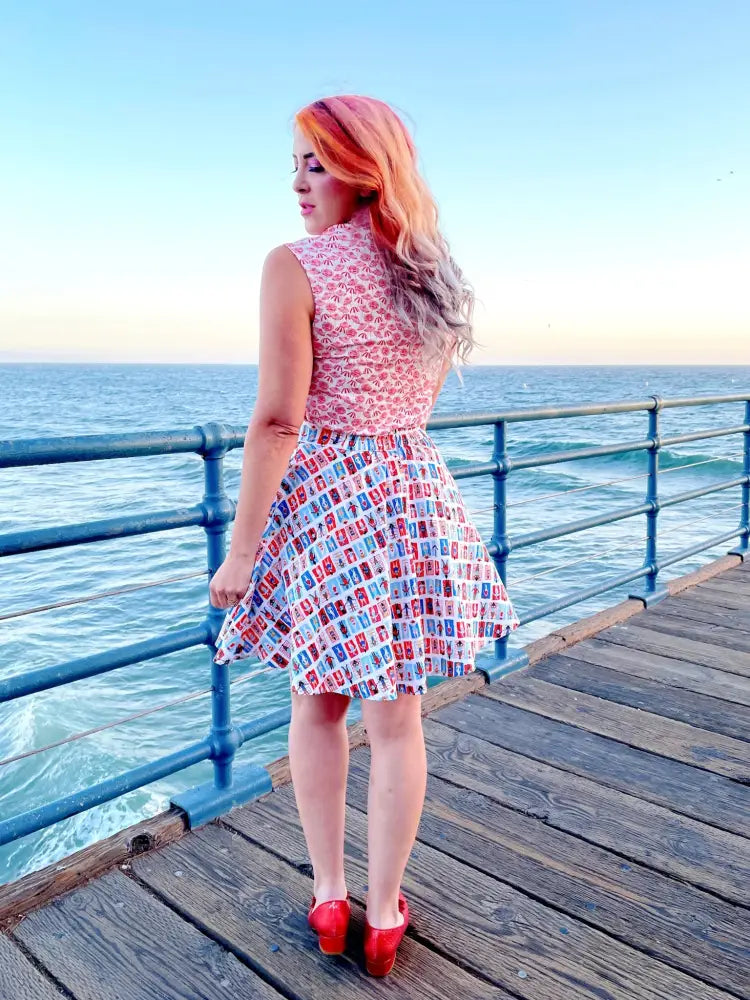 A sleeveless knee-length dress with pink and white fabric featuring red blue and black vintage phone designs