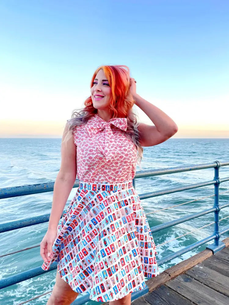 A woman wearing a sleeveless pink and white vintage beach umbrella print bow neckline blouse with colorful soda can pattern