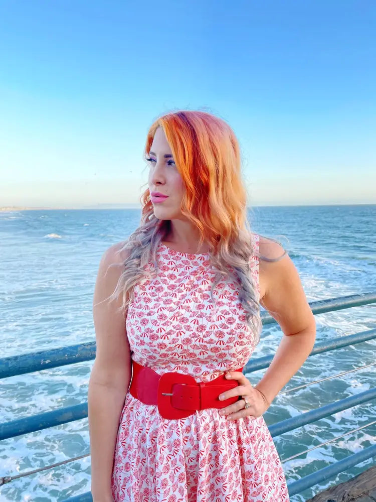 A vibrant red wide-belted vintage umbrella print pink floral midi dress with a large rectangular buckle belt