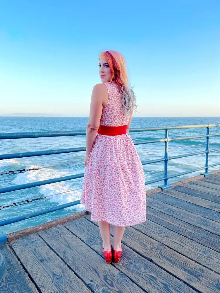 Pink floral midi dress with vintage umbrella print, red belt, and matching red heels for a stylish look