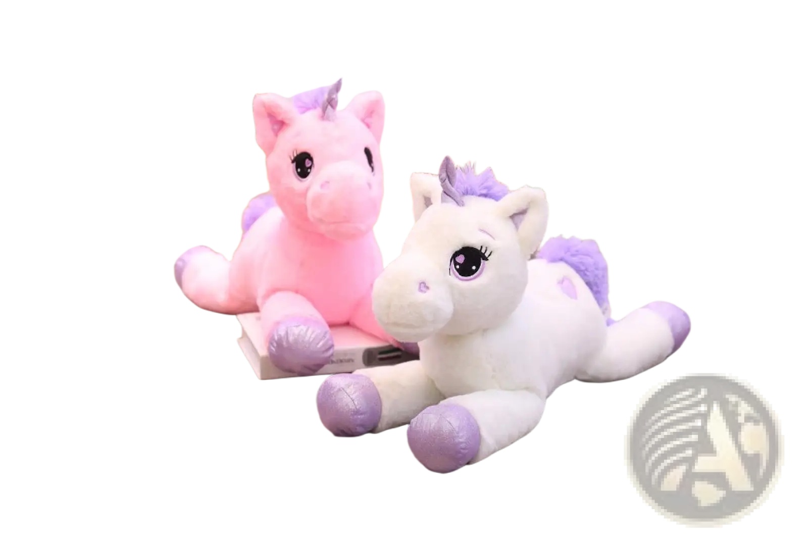 Soft pink and white plush unicorns with purple accents and embroidered eyes lie on a wooden floor stuffed animal