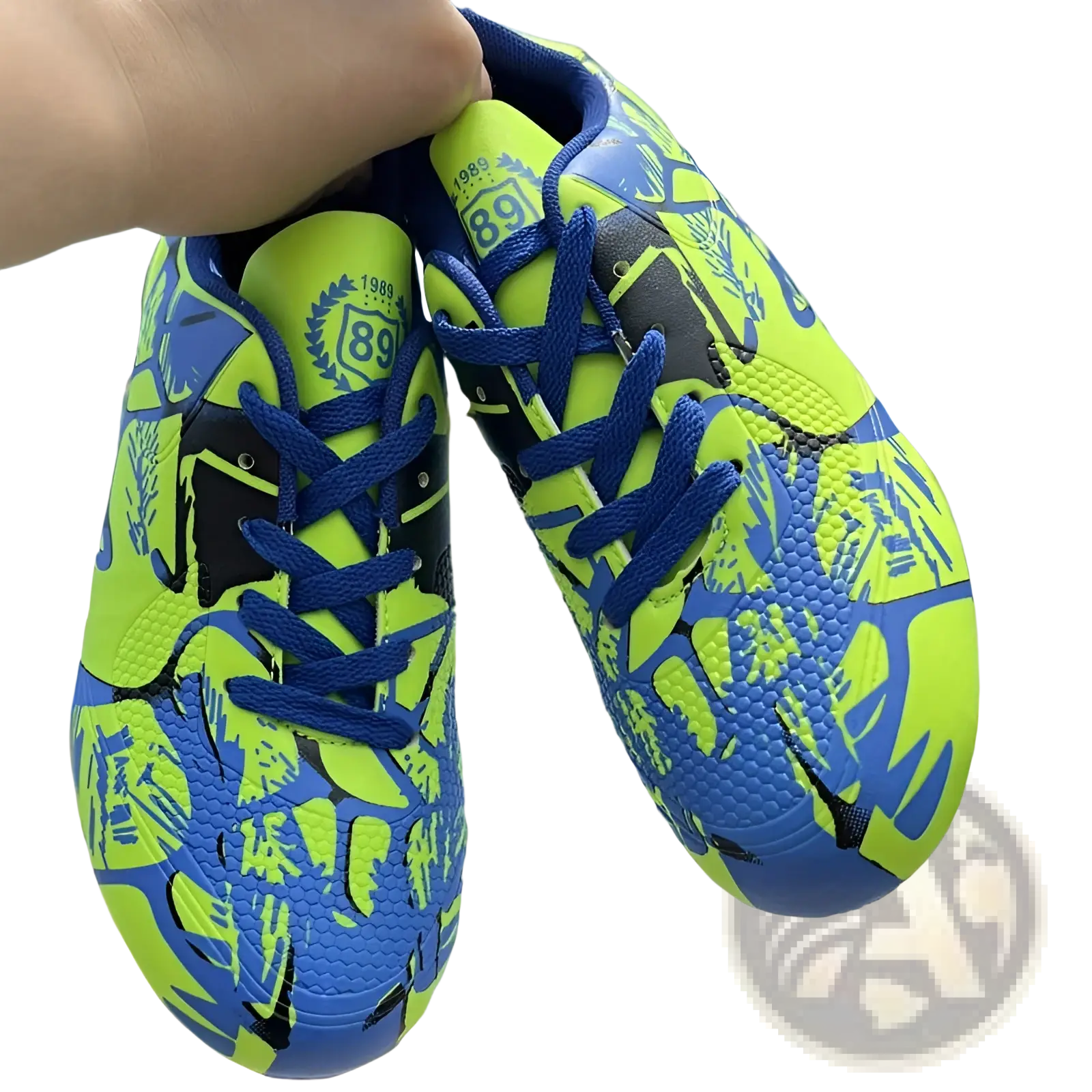 Unisex neon graphic low top soccer cleats in vibrant neon green and royal blue with bold black patterns for all terrains