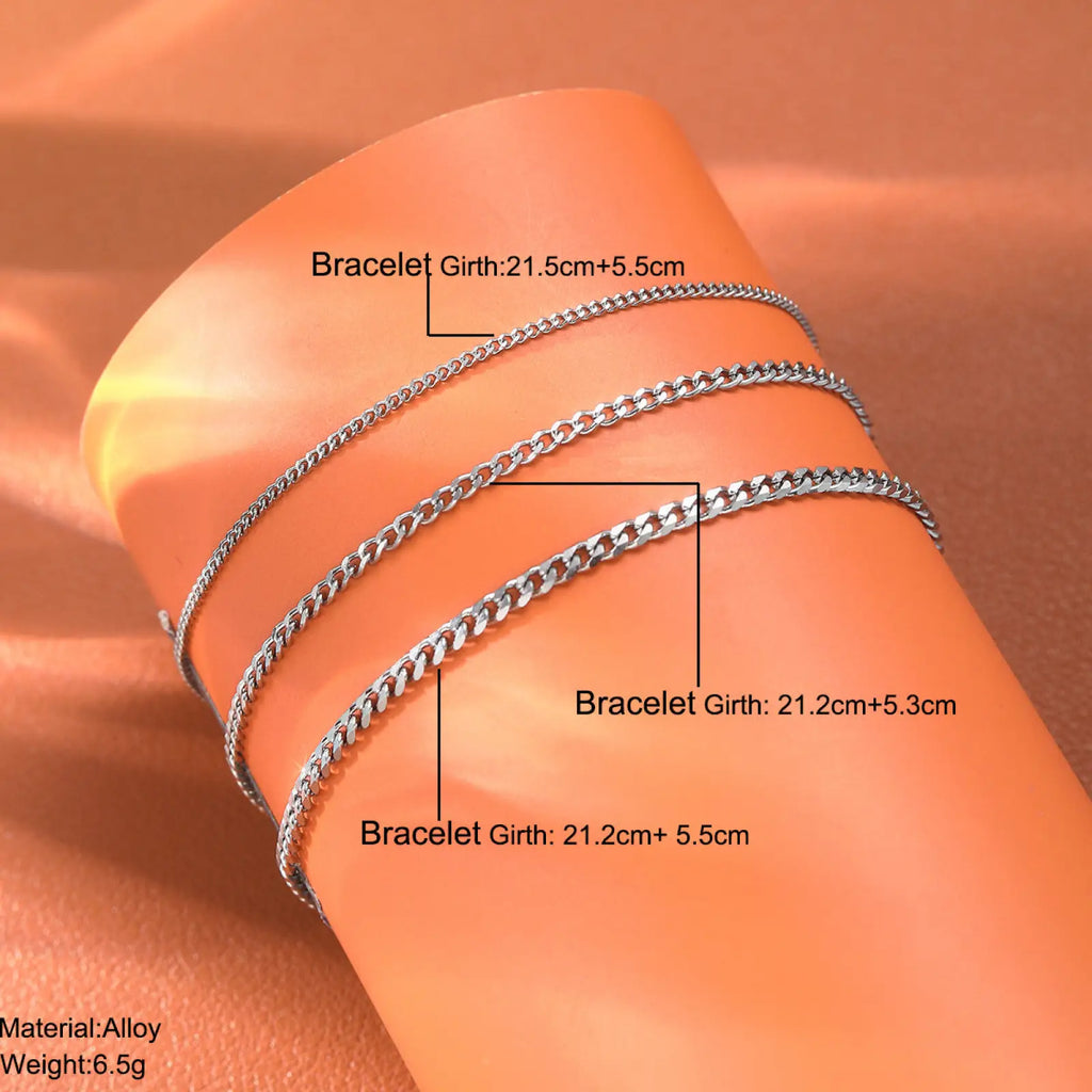 Unisex silver layered Cuban and Figaro link bracelet set featuring three silver-toned chain bracelets on wrist