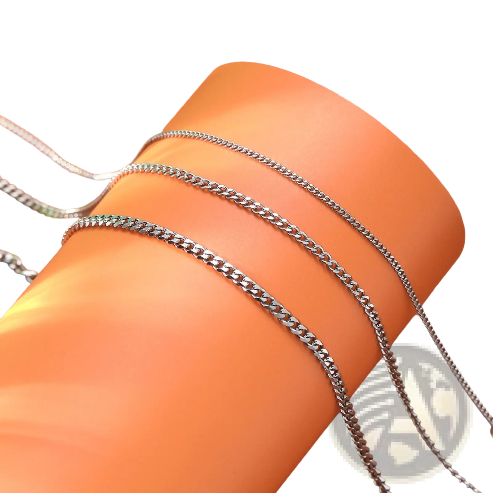 Unisex silver layered Cuban and Figaro link bracelet set with silver-toned curb chain necklaces on orange surface