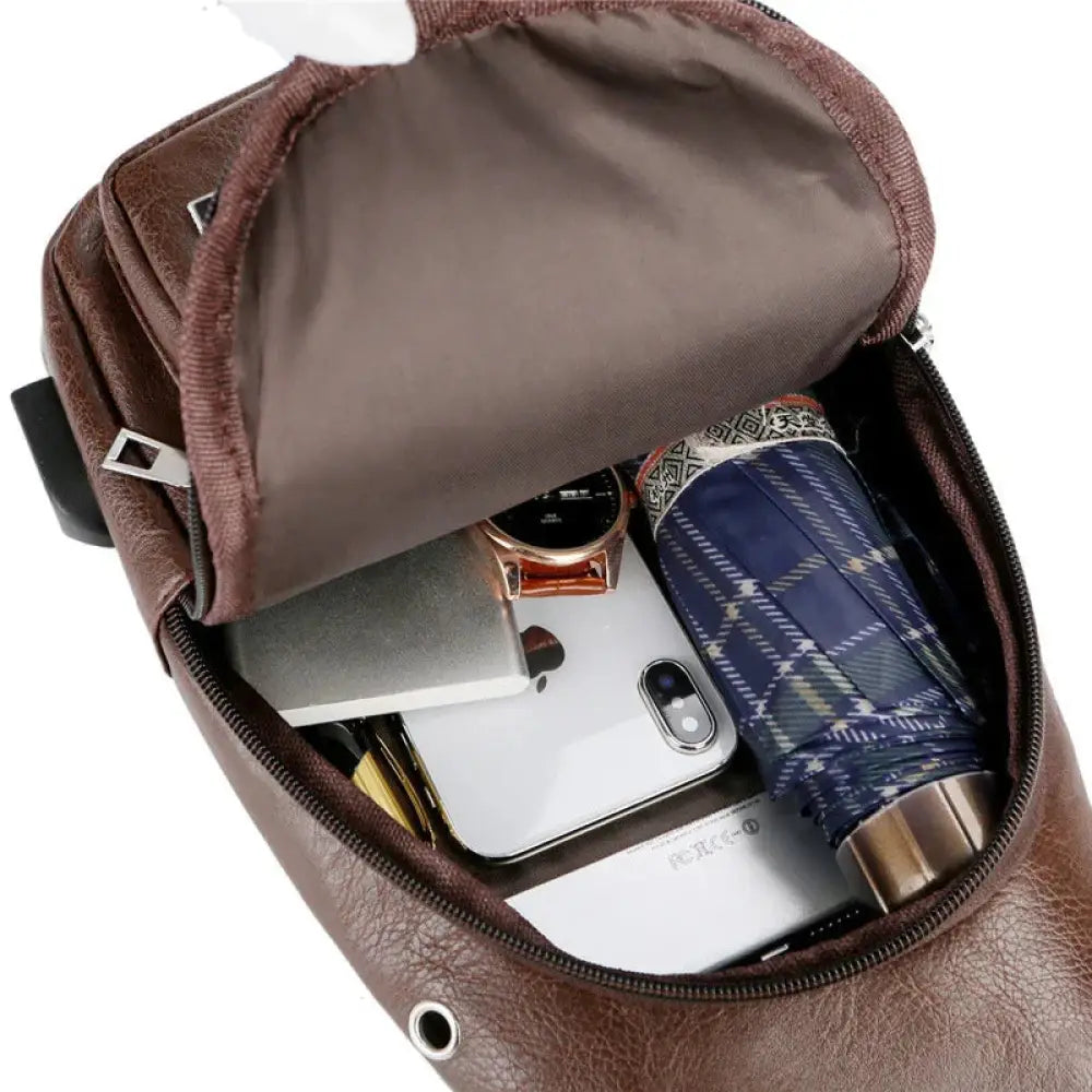 Brown faux leather usb charging chest messenger bag with zippered compartment holding smartphone and personal items
