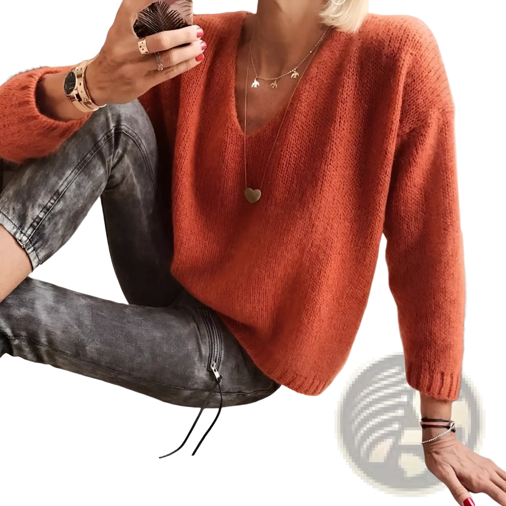 A cozy v-neck drop-shoulder knit sweater in rust-orange with a soft fuzzy texture and long sleeves