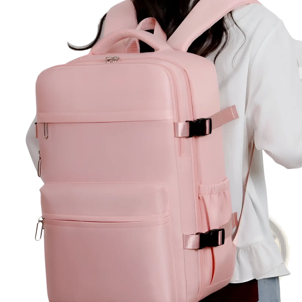 A sleek blush pink nylon vacuum compression laptop backpack 15 inch 35l with black buckle straps and silver zippers