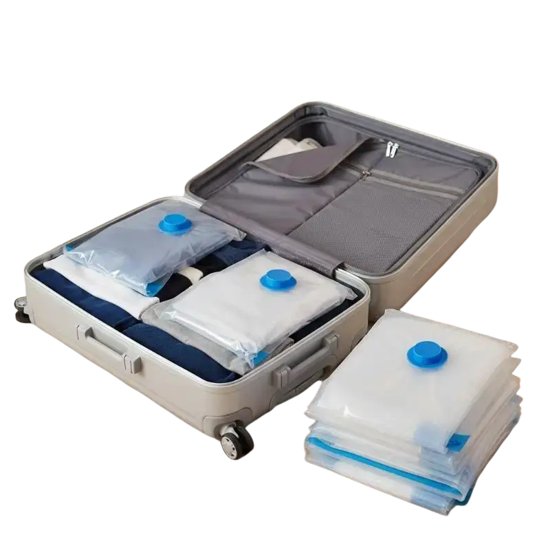 Clear plastic pa+pe material vacuum storage bags with blue caps and sealing strips stacked beside an open suitcase