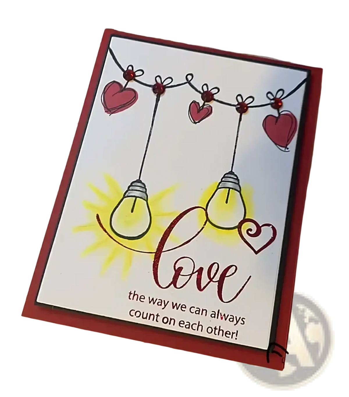 A red-bordered handmade valentine clear stamp card with hand-drawn pink heart string lights and glittery love script