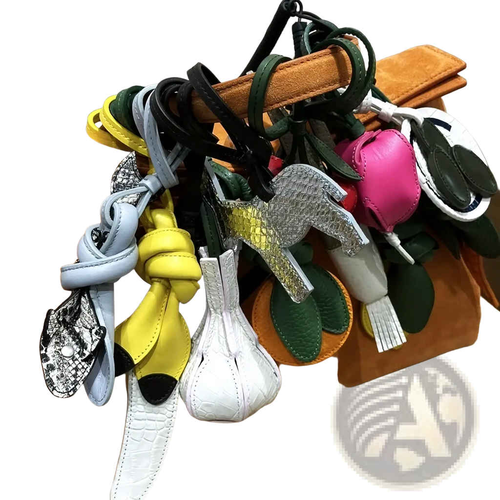 A collection of colorful vegetable leather handbag charms with intricate designs hanging from a tan suede handle