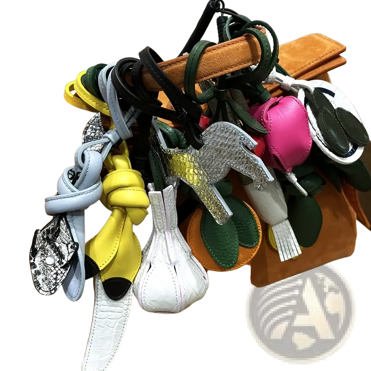 A collection of colorful vegetable leather handbag charms with intricate designs hanging from a tan suede handle