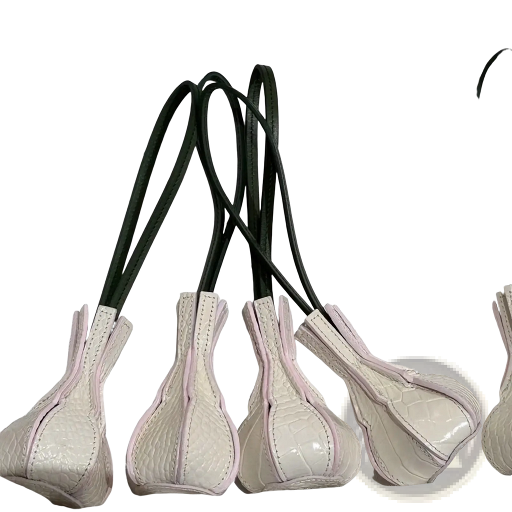 Cream-colored crocodile-embossed vegetable leather handbag handles with pink stitching and dark green straps for designer purse charms