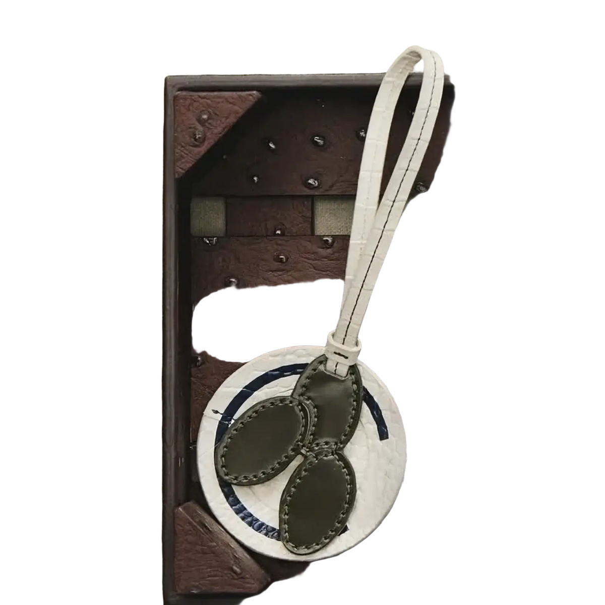 White circular vegetable leather luggage tag with olive green stitched leaf accents and matching strap for handbags