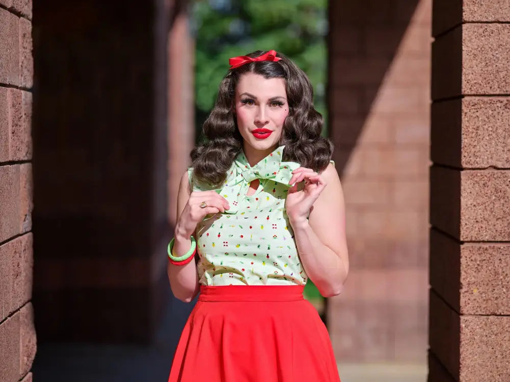 A woman wearing a vintage green veggie print bow blouse with playful candy patterns paired with a red skirt