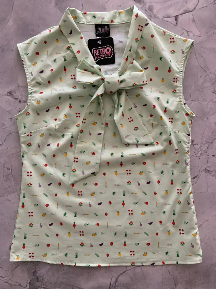 Sleeveless light green vintage blouse with playful fruit and vegetable print including cherries pineapples and eggplants