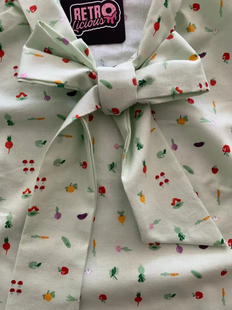 Vintage green veggie print bow blouse made of mint green fabric with colorful fruit and vegetable pattern tied at neckline