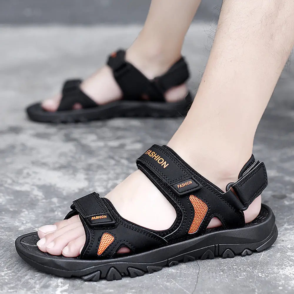 Men’s breathable athletic black and orange sandals with adjustable velcro straps and textured rubber sole for beach use