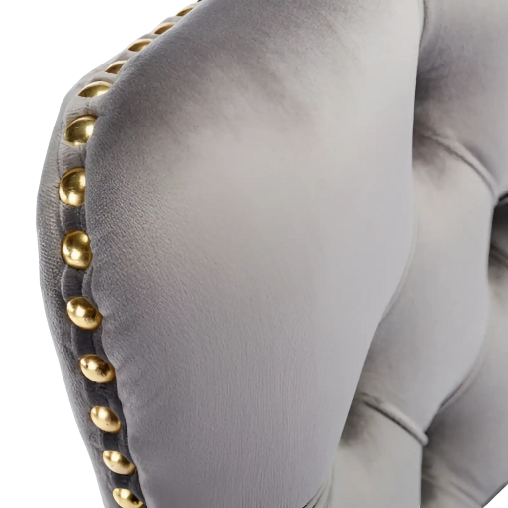 Gray velvet office chair armrest with gold toned nailhead trim showcasing tufted design and swivel functionality