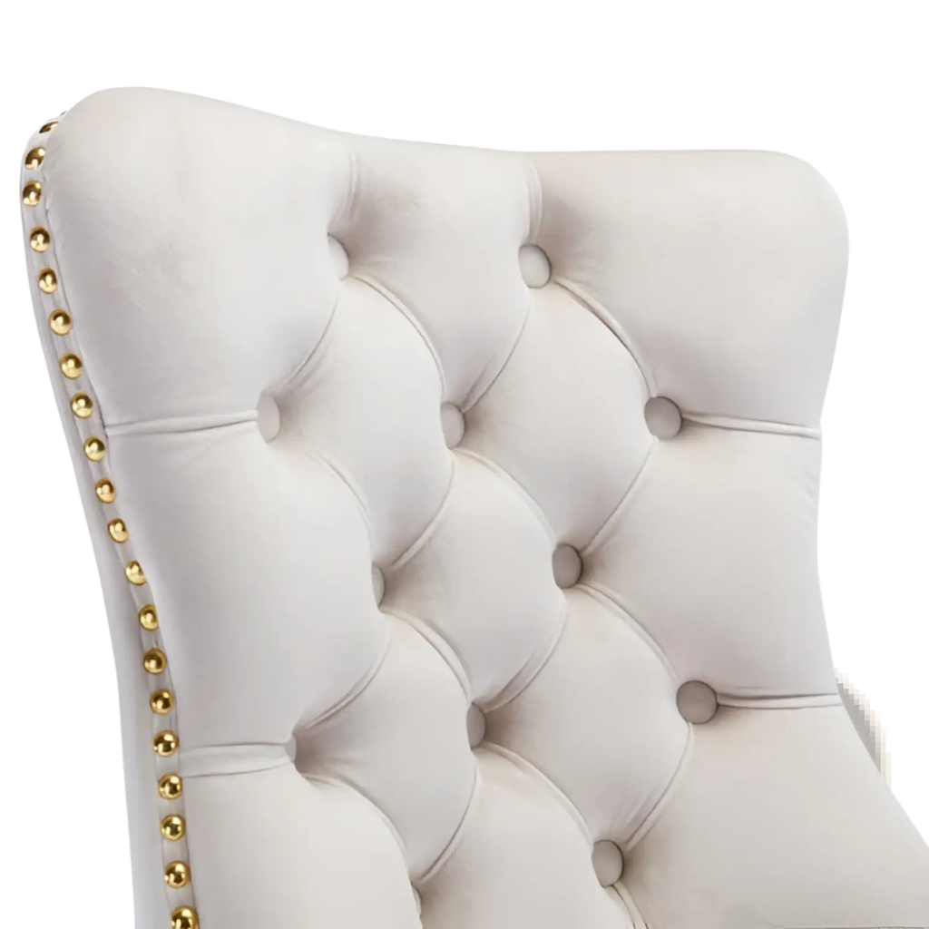 Back side of a cream-colored velvet tufted office chair with gold nailhead trim and gold base beige