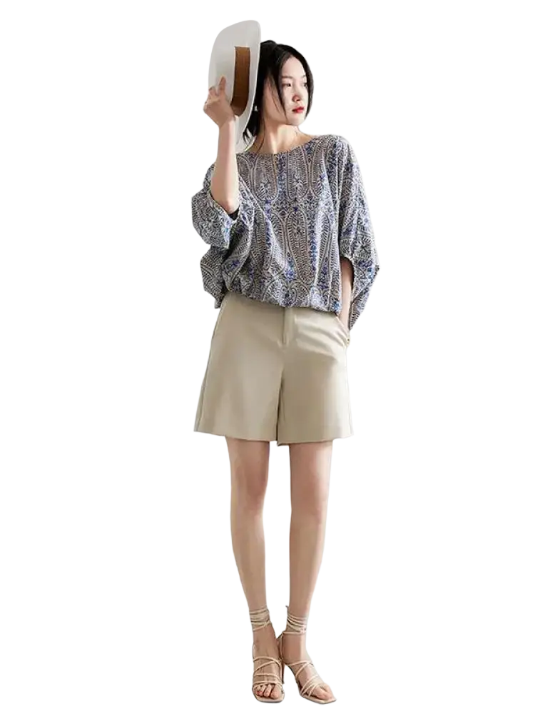A woman wears a vintage bow batwing chiffon blouse with an intricate blue and white paisley pattern and loose fit