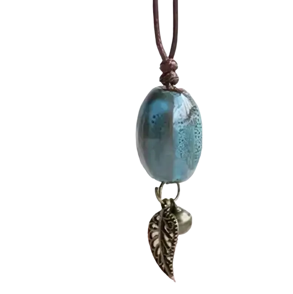 Vintage ceramic leaf pendant necklace featuring a blue glass bead, metallic leaf charm, and small bell on brown cord