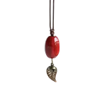 Vintage ceramic leaf pendant necklace for women featuring a red oval bead and silver charm on dark brown cord
