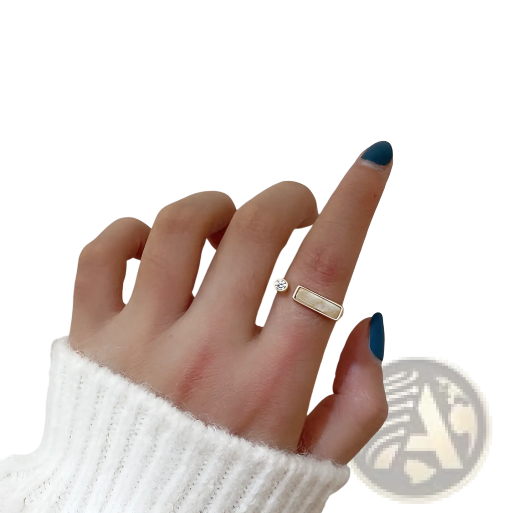 A delicate gold-toned adjustable ring featuring a small round zircon and a rectangular textured marble stone accent