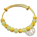 Delicate gold plated chalcedony bangle bracelet featuring pale green jade beads and intricate gold floral charms