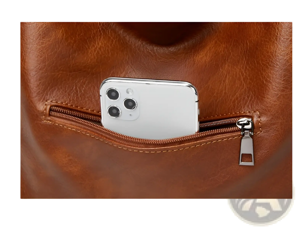 Brown leather vintage tote bag multi pocket shoulder purse shown from back with zip pocket holding white smartphone