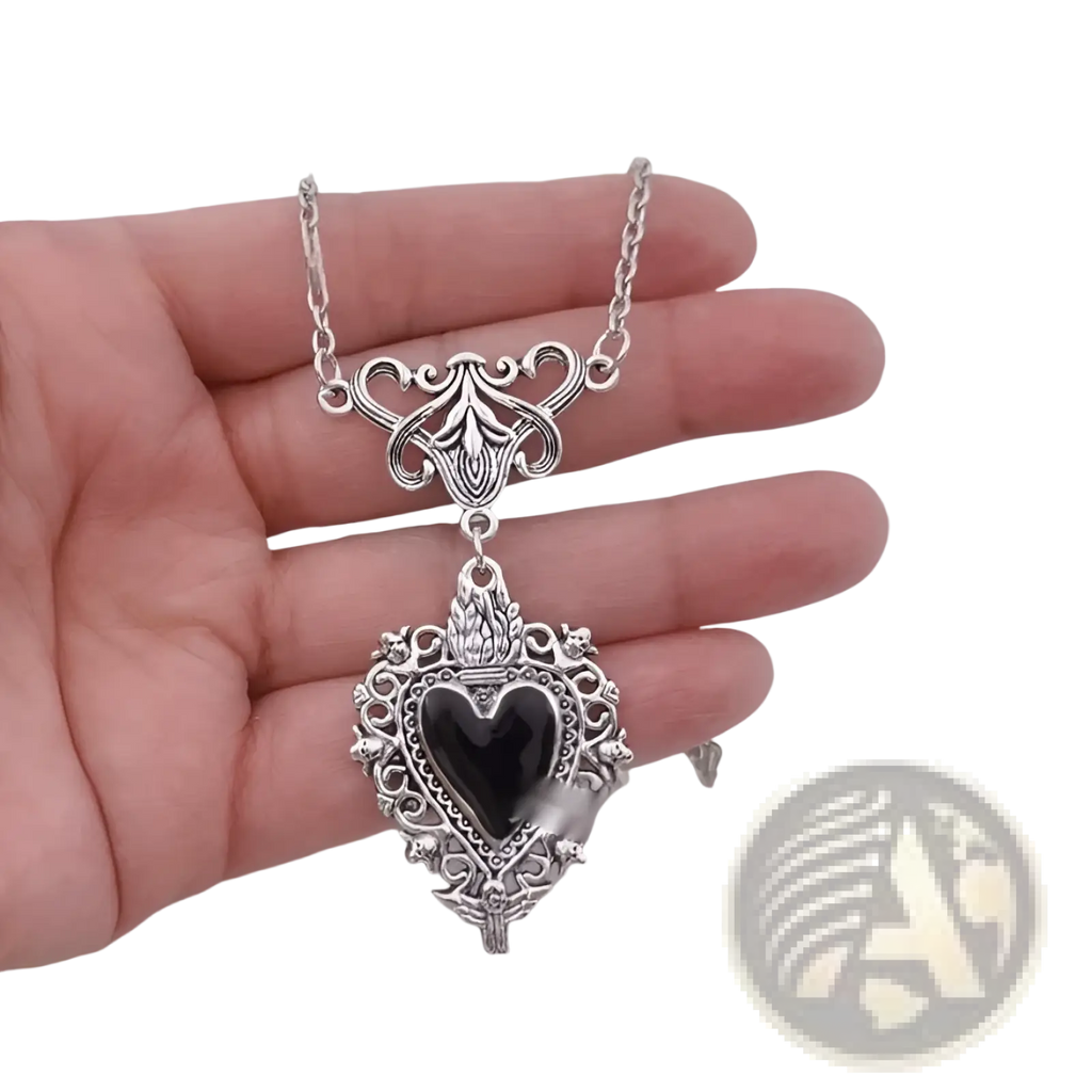 Silver heart-shaped pendant necklace with intricate filigree detailing and a black onyx center gemstone