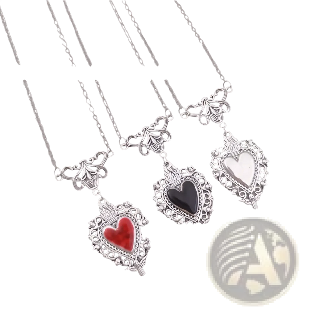 Vintage silver filigree heart pendant with intricate detailing and a central red enamel gemstone in an ornate frame