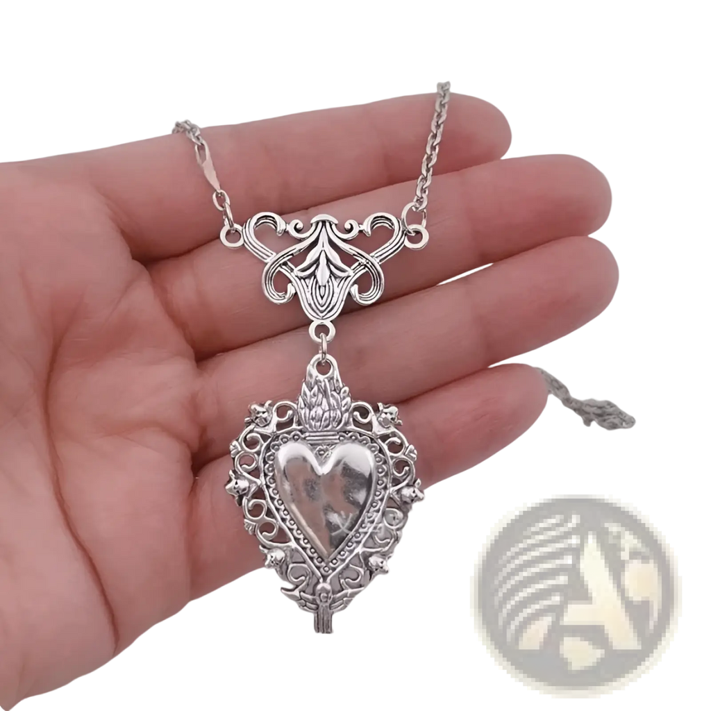 Vintage silver filigree heart pendant necklace with intricate detailing and decorative chain featuring red enamel center
