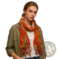 A vibrant orange and green lightweight viscose scarf with tie dye print and frayed edges worn loosely around the neck