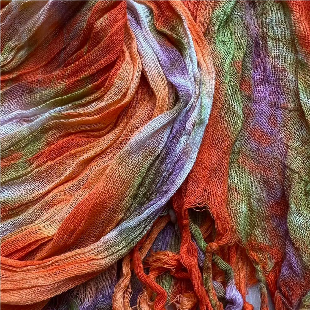 A vibrant loosely woven lightweight viscose scarf with orange green purple and white tie dye print for dress accessory